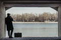 handsome adult man with suitcase smoking in tunnel in front of