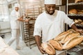 handsome african american baker taking bread loaves from oven Royalty Free Stock Photo