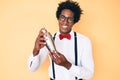Handsome african american bartender man with afro hair preparing cocktail mixing drink with shaker smiling with a happy and cool