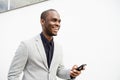 Handsome African American business man smiling with mobile phone by white wall Royalty Free Stock Photo