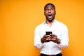 Handsome african american businessman holding a phone in his hands and looking at the camera surprised Royalty Free Stock Photo