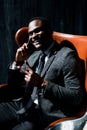 Handsome african american businessman sitting on chair and talking on the phone showing peace sign Royalty Free Stock Photo