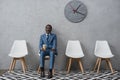 Handsome African american businessman sitting in a waiting room and holding coffee in a Royalty Free Stock Photo