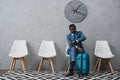 Handsome African american businessman sitting in a waiting room with suitcase and looking Royalty Free Stock Photo
