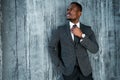 Handsome african american businessman in a suit looks to the side while straightening a tie around his neck Royalty Free Stock Photo