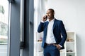 Handsome african american businessman talking on mobile phone in modern office. Royalty Free Stock Photo