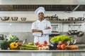 handsome african american chef standing at restaurant kitchen with crossed arms and looking Royalty Free Stock Photo