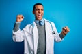 Handsome african american doctor man wearing coat and stethoscope over blue background Dancing happy and cheerful, smiling moving Royalty Free Stock Photo