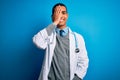 Handsome african american doctor man wearing coat and stethoscope over blue background looking at the camera smiling with open Royalty Free Stock Photo