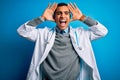 Handsome african american doctor man wearing coat and stethoscope over blue background Smiling cheerful playing peek a boo with Royalty Free Stock Photo