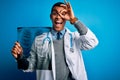 Handsome african american doctor man wearing stethoscope holding chest xray with happy face smiling doing ok sign with hand on eye Royalty Free Stock Photo