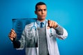 Handsome african american doctor man wearing stethoscope holding chest xray pointing with finger to the camera and to you, hand Royalty Free Stock Photo