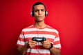 Handsome african american gamer man playing video game using jostick and headphones with a confident expression on smart face Royalty Free Stock Photo