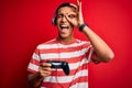 Handsome african american gamer man playing video game using jostick and headphones with happy face smiling doing ok sign with Royalty Free Stock Photo