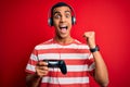 Handsome african american gamer man playing video game using jostick and headphones screaming proud and celebrating victory and Royalty Free Stock Photo