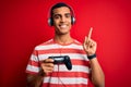 Handsome african american gamer man playing video game using jostick and headphones surprised with an idea or question pointing Royalty Free Stock Photo