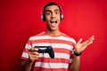 Handsome african american gamer man playing video game using jostick and headphones very happy and excited, winner expression Royalty Free Stock Photo