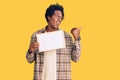 Handsome african american man with afro hair holding blank empty banner pointing thumb up to the side smiling happy with open Royalty Free Stock Photo