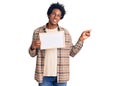 Handsome african american man with afro hair holding blank empty banner smiling happy pointing with hand and finger to the side Royalty Free Stock Photo