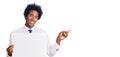 Handsome african american man with afro hair holding blank empty banner smiling happy pointing with hand and finger to the side Royalty Free Stock Photo