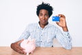 Handsome african american man with afro hair holding credit card and piggy bank depressed and worry for distress, crying angry and Royalty Free Stock Photo