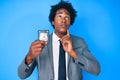 Handsome african american man with afro hair holding detective badge serious face thinking about question with hand on chin,