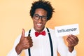 Handsome african american man with afro hair holding paper with influencer text smiling happy and positive, thumb up doing