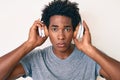 Handsome african american man with afro hair listening to music using headphones relaxed with serious expression on face Royalty Free Stock Photo