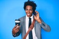 Handsome african american man with afro hair using smartphone and drinking a cup of coffee smiling and laughing hard out loud Royalty Free Stock Photo