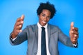 Handsome african american man with afro hair wearing business jacket looking at the camera smiling with open arms for hug Royalty Free Stock Photo