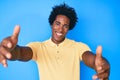 Handsome african american man with afro hair wearing casual clothes looking at the camera smiling with open arms for hug Royalty Free Stock Photo