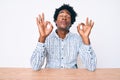 Handsome african american man with afro hair wearing casual clothes sitting on the table relax and smiling with eyes closed doing Royalty Free Stock Photo