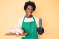 Handsome african american man with afro hair wearing cook apron and holding chicken winking looking at the camera with sexy Royalty Free Stock Photo