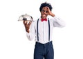 Handsome african american man with afro hair wearing waiter uniform holding silver tray smiling happy doing ok sign with hand on Royalty Free Stock Photo