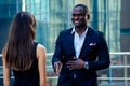 Handsome African American man in a black business suit shaking hand with a businesswoman partner cityscape glass offices Royalty Free Stock Photo