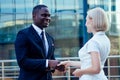 Handsome African American man in a black business suit shaking hand with a businesswoman partner cityscape glass offices Royalty Free Stock Photo