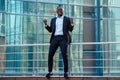 A handsome African American man in a black stylish suit and a white shirt rejoicing in success and thanking God against Royalty Free Stock Photo