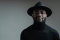 Handsome african american man in a hat wearing glasses and in a black turtleneck smiling looking at the camera Royalty Free Stock Photo