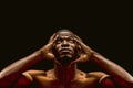 Handsome African american man looking up touching hands of head, portrait of nude dark-skinned athlete isolated on black Royalty Free Stock Photo