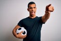 Handsome african american man playing footbal holding soccer ball over white background pointing displeased and frustrated to the Royalty Free Stock Photo