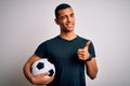 Handsome african american man playing footbal holding soccer ball over white background pointing fingers to camera with happy and Royalty Free Stock Photo