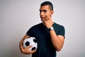Handsome african american man playing footbal holding soccer ball over white background Pointing to the eye watching you gesture, Royalty Free Stock Photo