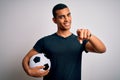 Handsome african american man playing footbal holding soccer ball over white background pointing to you and the camera with Royalty Free Stock Photo