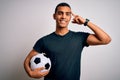 Handsome african american man playing footbal holding soccer ball over white background Smiling pointing to head with one finger, Royalty Free Stock Photo