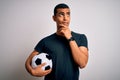 Handsome african american man playing footbal holding soccer ball over white background Thinking worried about a question, Royalty Free Stock Photo