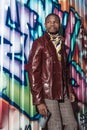 Handsome african american man in stylish clothes posing in front of graffiti wall and holding a spray Royalty Free Stock Photo