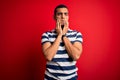Handsome african american man wearing casual striped t-shirt standing over red background Tired hands covering face, depression Royalty Free Stock Photo