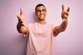 Handsome african american man wearing casual t-shirt and glasses over pink background looking at the camera smiling with open arms Royalty Free Stock Photo