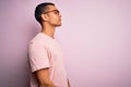 Handsome african american man wearing casual t-shirt and glasses over pink background looking to side, relax profile pose with Royalty Free Stock Photo