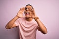Handsome african american man wearing casual t-shirt and glasses over pink background Shouting angry out loud with hands over Royalty Free Stock Photo